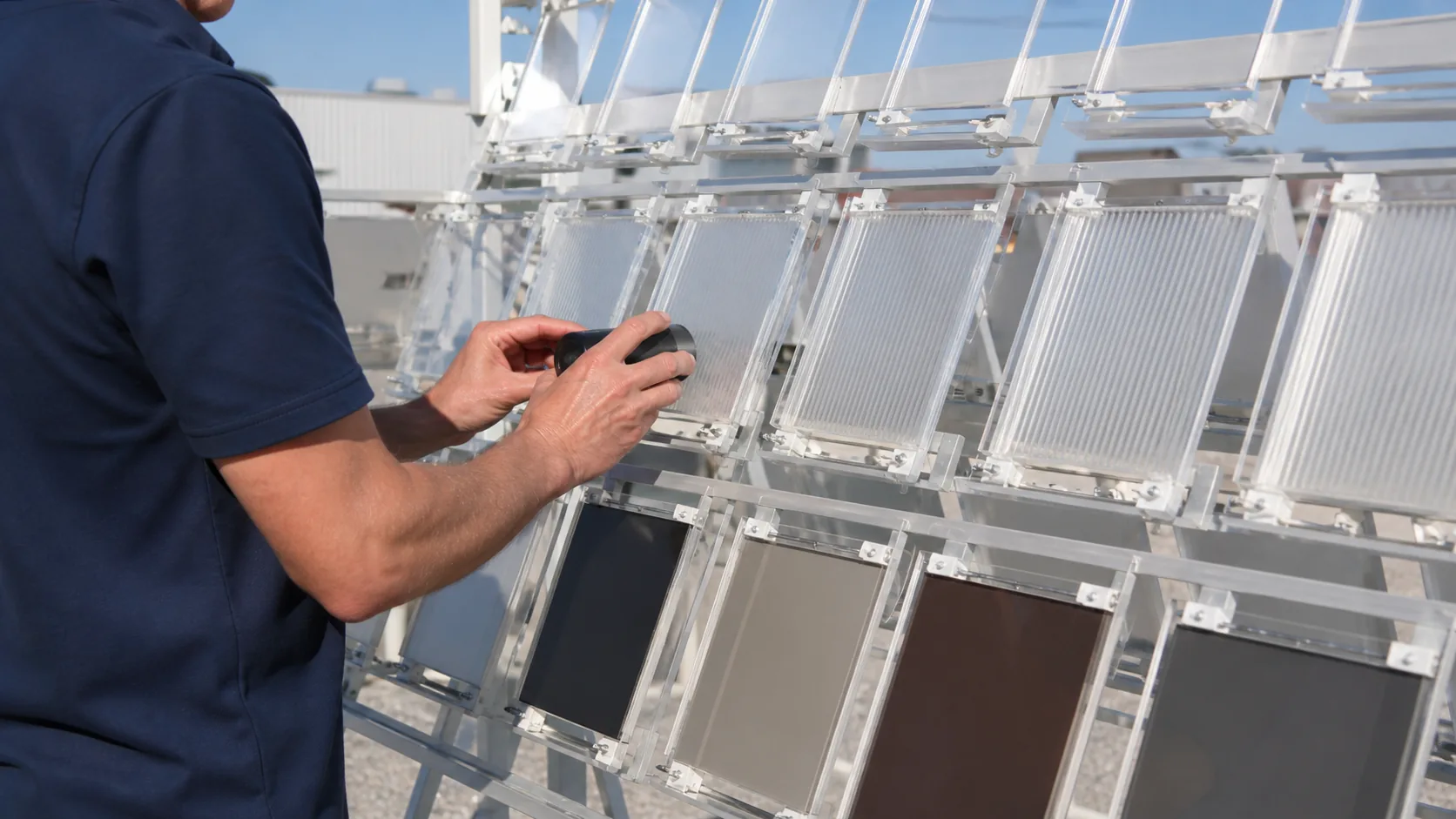 Clear polymer panels inspected on an outdoor weathering rack